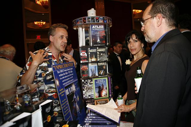 Richard Godwin (L), founder and co owner of CG Publishing and NSS Director, talks with visitors at the Red Planet Adventures exhibit at the Space Venture Finance Symposium reception, a part of the International Space Development Conference